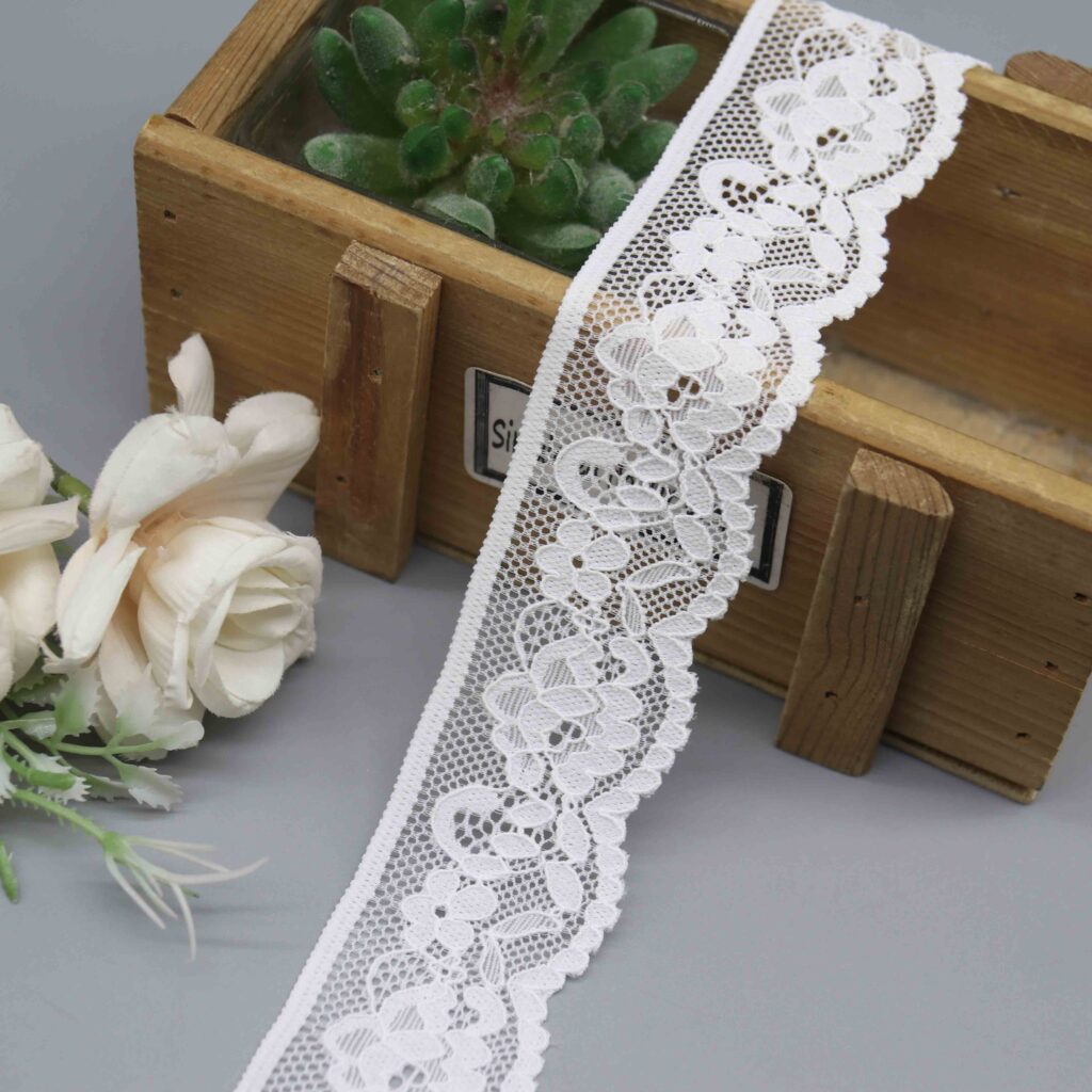 A studio shot of a 3.7cm white elastic lace trim, model HDL-1195, featuring a classic asymmetrical floral vine pattern.