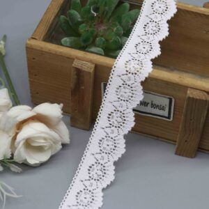A studio product photograph of a 2.6cm white picot edge stretch lace, showing its asymmetrical design with one straight edge and one scalloped edge.