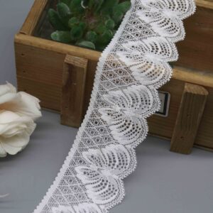 A studio product shot of a 4.6cm wide white scalloped stretch lace trim featuring a distinctive fan pattern, displayed in a wooden box.