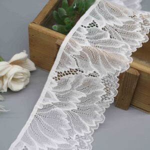 A close-up studio shot of a 7cm wide white elastic lace trim featuring a modern abstract wave pattern and scalloped edge.