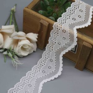 Studio product photo of a 4.5cm wide white stretch lace trim with symmetrical scalloped edges and a floral eyelet pattern.