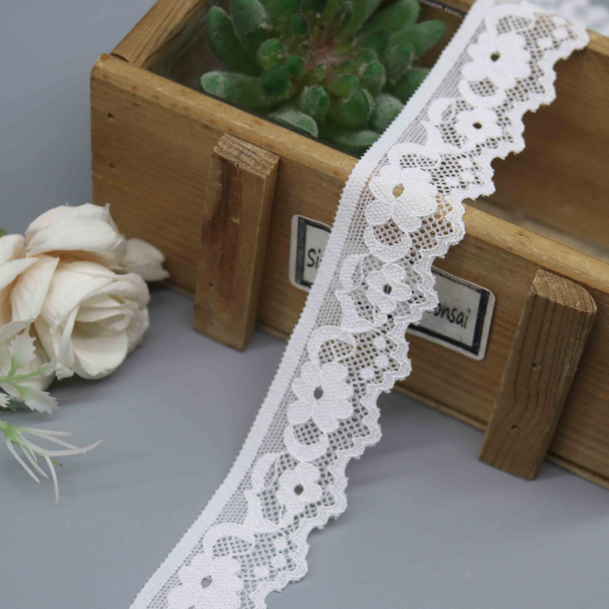 A close-up product photo of a 2.7cm white galloon lace trim, model HDL-1418, with a simple floral pattern