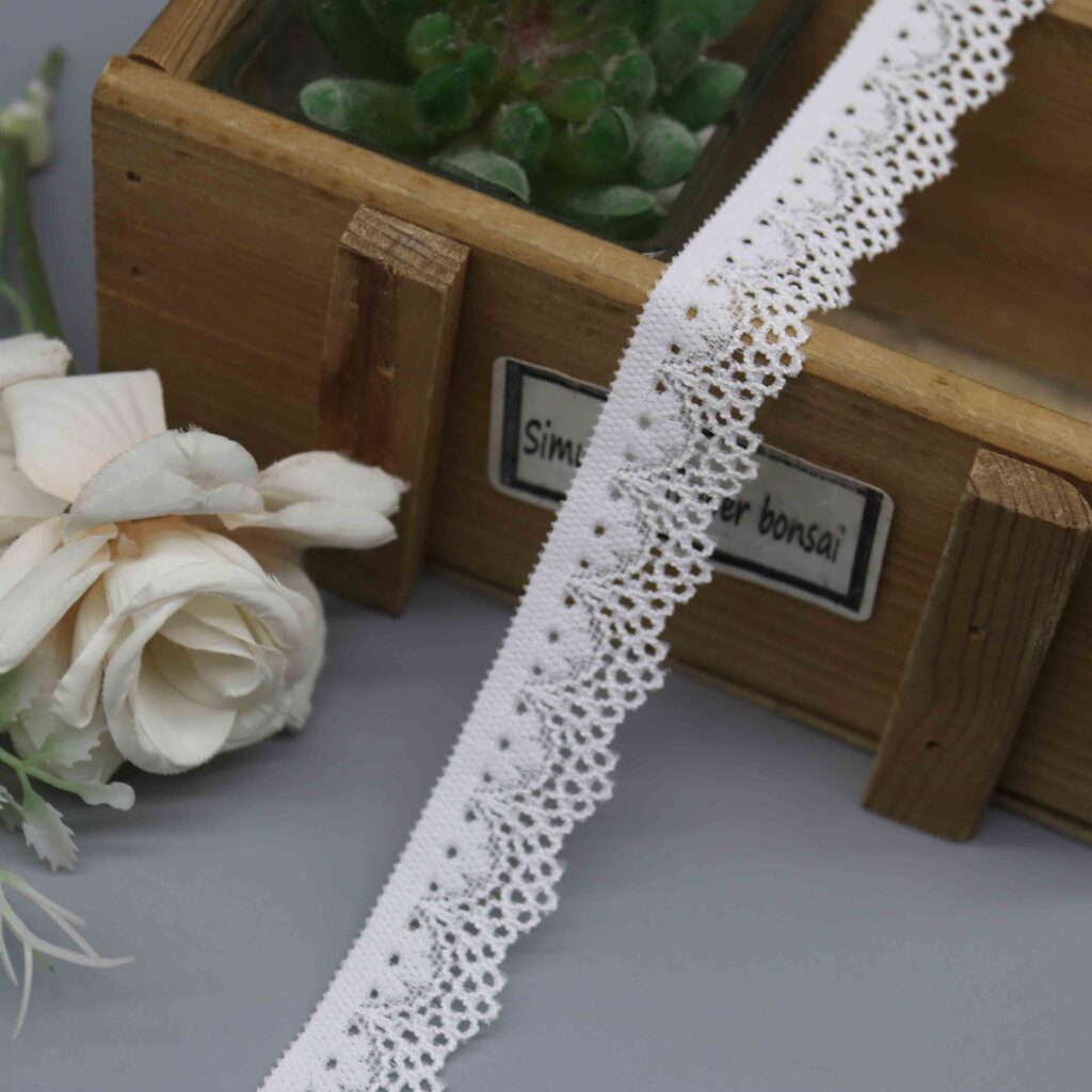 A close-up studio shot of a 2cm narrow elastic lace, model HDL-1048, displayed on a grey background to show its fine pattern.