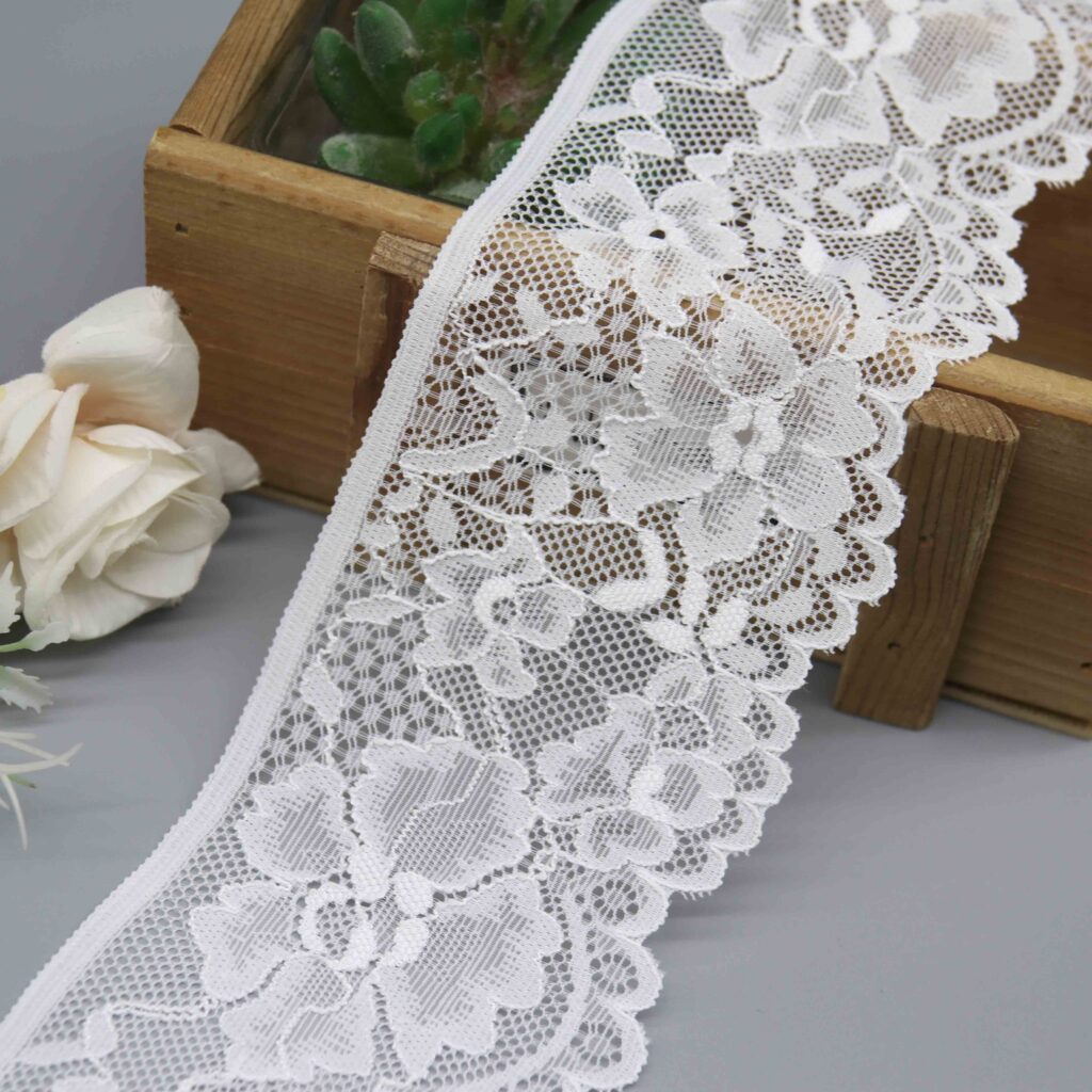 a 7.5cm wide stretch lace in white, featuring a dense floral pattern and scalloped edges.