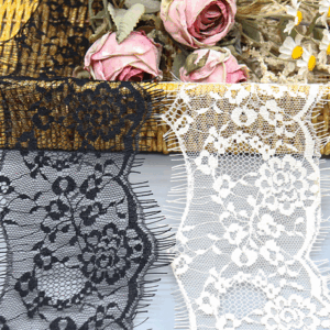 Close-up of factory-wholesale nylon eyelash lace trim in black and white, featuring intricate mesh embroidery with layered floral motifs for a 3D effect, and delicate, elongated eyelash fringe edges for added luxury; soft and breathable, ideal for high-end dress embellishments.