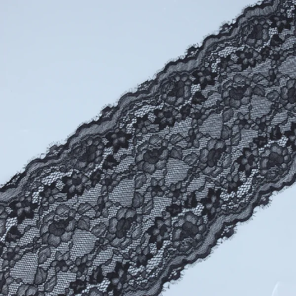 Close-up of black eyelash lace edged with fine eyelash fringes and floral mesh design, 21 cm wide.