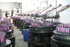 Factory floor showing a worker and weaving machinery surrounded by lace materials.
