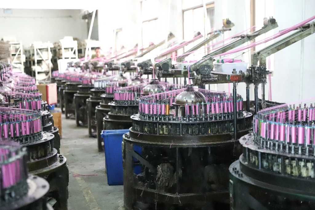 Factory floor showing a worker and weaving machinery surrounded by lace materials.