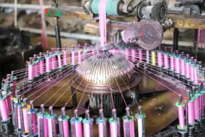 Employee threading yarn into industrial lace-making equipment.