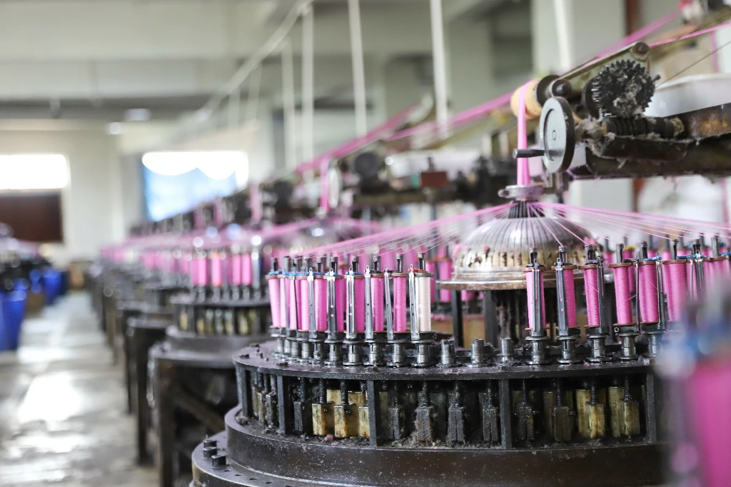 Employee managing lace weaving machine in the production workshop.