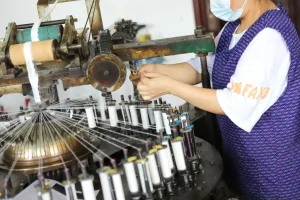 Textile worker handling threads and spools at a lace production facility.