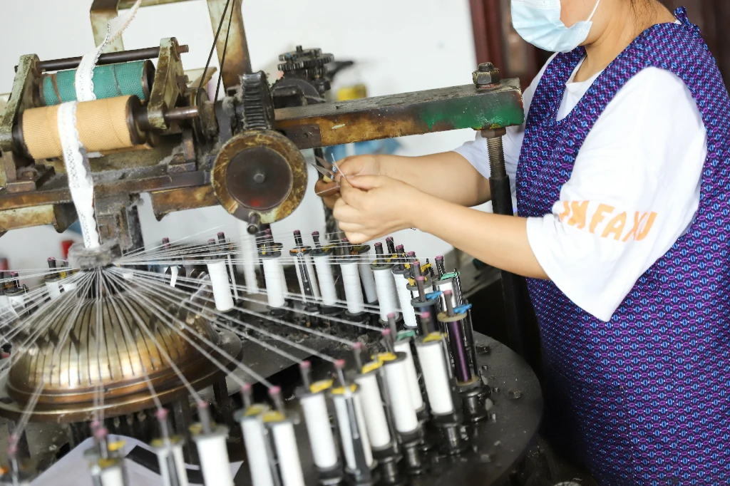 Textile worker handling threads and spools at a lace production facility.