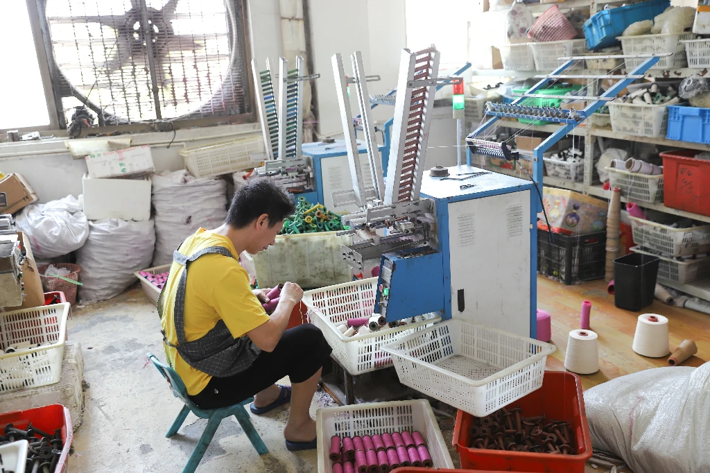 Factory worker operating lace manufacturing machine during production.