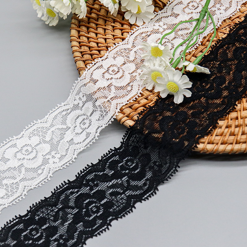 Black and white lace trims featuring elegant floral designs displayed on a woven tray with white daisies.