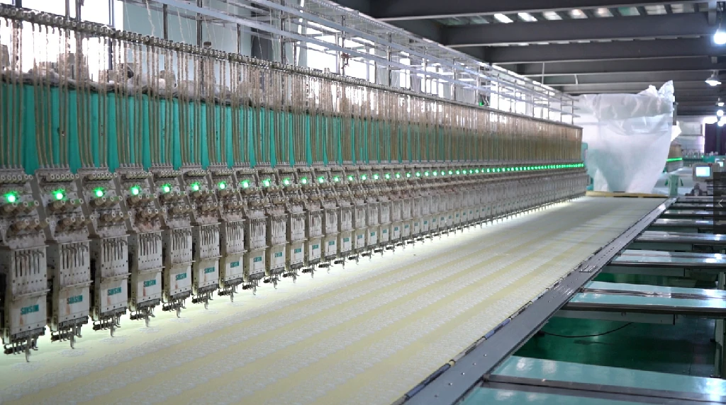 Interior view of a lace embroidery factory equipped with high-speed automated machines producing intricate lace trims for various industries.