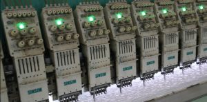 Panoramic image of a large lace manufacturing plant featuring multiple embroidery lines working simultaneously to produce fine lace products.