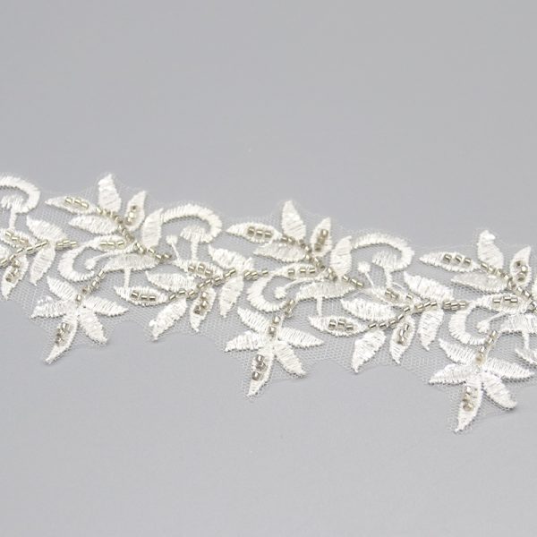 Elegant white lace trim showcasing detailed leaf embroidery and sparkling bead decorations, suitable for bridal wear.