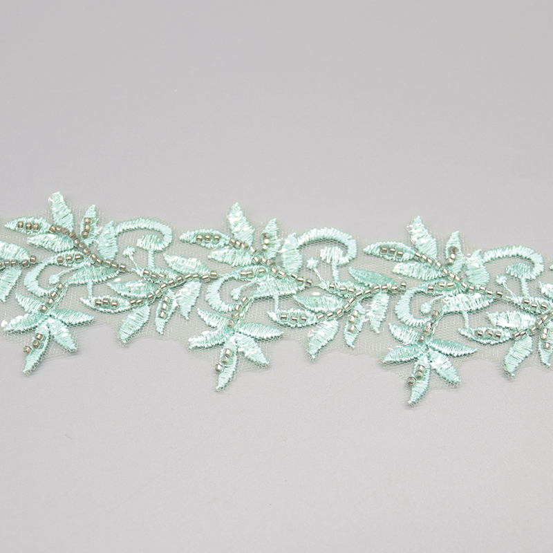 Light green embroidered lace featuring beaded leaf motifs, adding a delicate and romantic touch to garments.