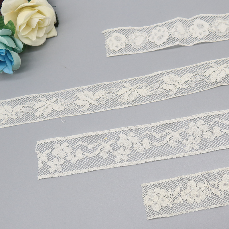 Glossy fancy lace trim and vintage crocheted lace attached to white wedding invitations, providing unique edge options for upscale stationery.