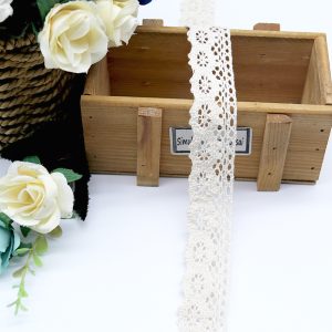 Close-up of exquisite cotton thread lace trim featuring delicate floral embroidery, perfect for couture fashion and elegant garment accents.