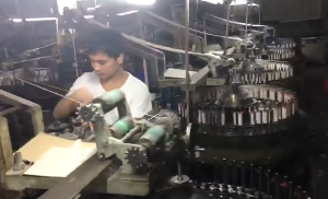 Wide-angle image of a cotton lace factory floor with automated embroidery machines creating durable border eyelet lace for wholesale orders.
