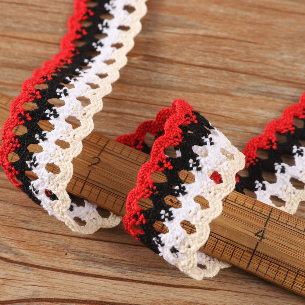 Close-up of black cotton eyelet lace trim featuring geometric holes and scalloped edges, perfect for statement garment edges and chic accessories.
