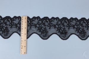 Rich black crocheted floral lace with bead detailing contrasted with classic black embroidered lace trim, providing dramatic texture for luxury apparel.