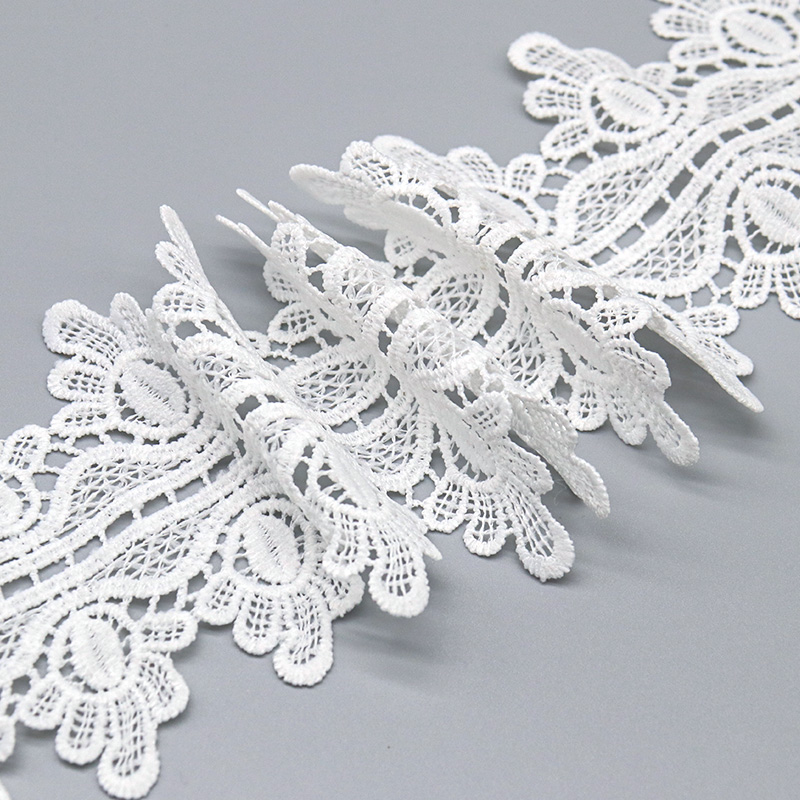 Macro view of sheer openwork water soluble lace next to a textured corded chemical lace border.
