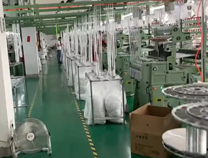 Interior view of a factory producing pure cotton embroidered eyelet lace trims, showing machines and rolls of durable border lace ready for bulk shipment.