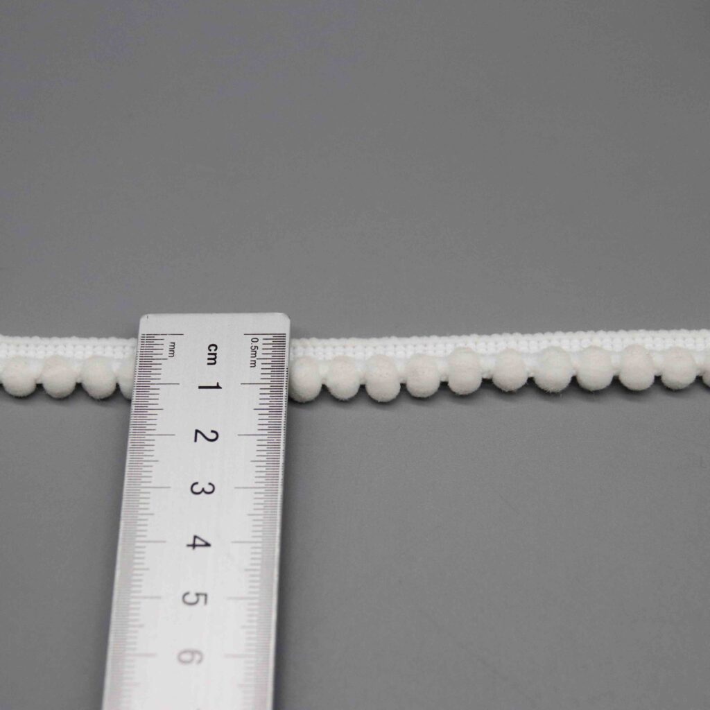 Ruler laid horizontally along the pompom spacing showing scale and ball distribution