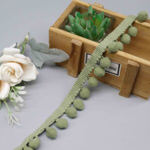 Front-facing shot of Olive Fuzzy Nylon Pompom Lace Trim, showing sage green pompom balls and braided bobble header clearly.