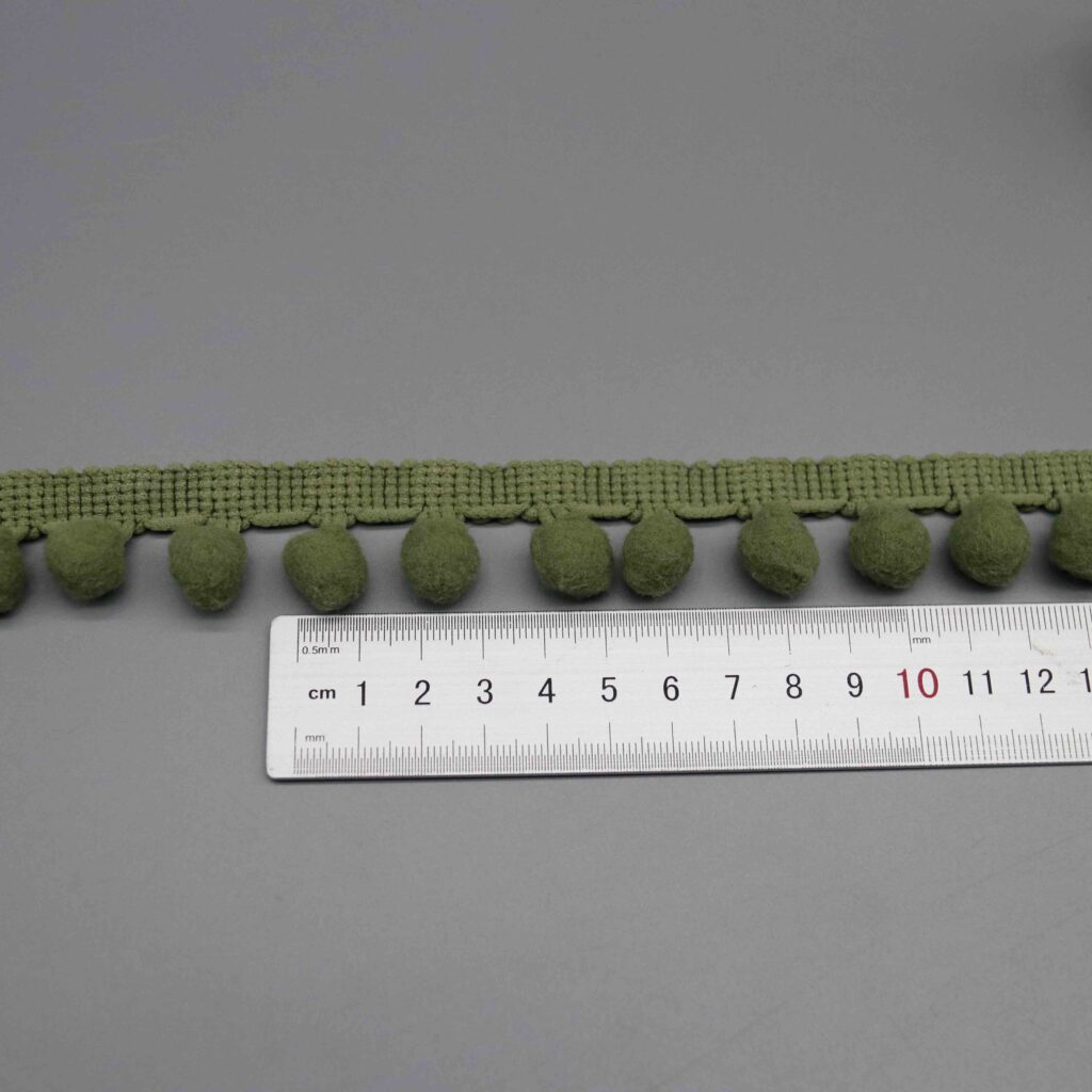 Ruler laid horizontally along the pompom spacing showing scale and ball distribution