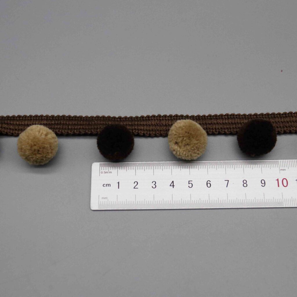 Ruler laid horizontally along the alternating pompom pattern showing color spacing and distribution