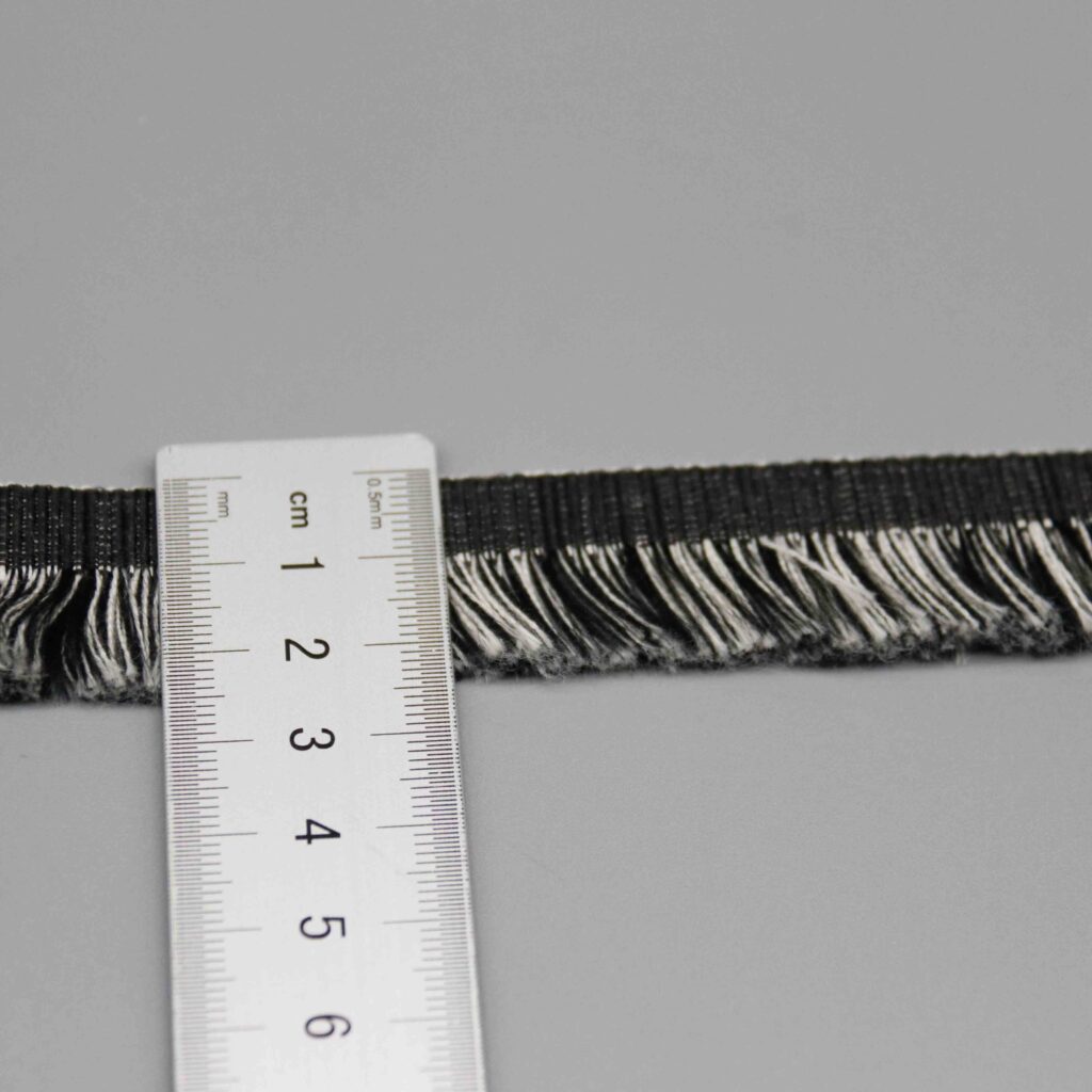 Ruler laid vertically across the fringe trim showing the exact 2.5cm width measurement