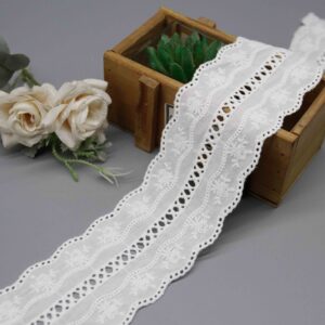 Front-facing shot showing scattered blossom embroidery and oval cutwork bands on white cotton broderie anglaise.