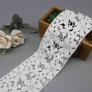 Front-facing shot showing lush floral arrangement and dimensional milk fiber texture on white water-soluble lace.