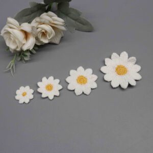 Front-facing shot showing dimensional white petal flower with golden yellow center on polyester-cotton embroidered motif.