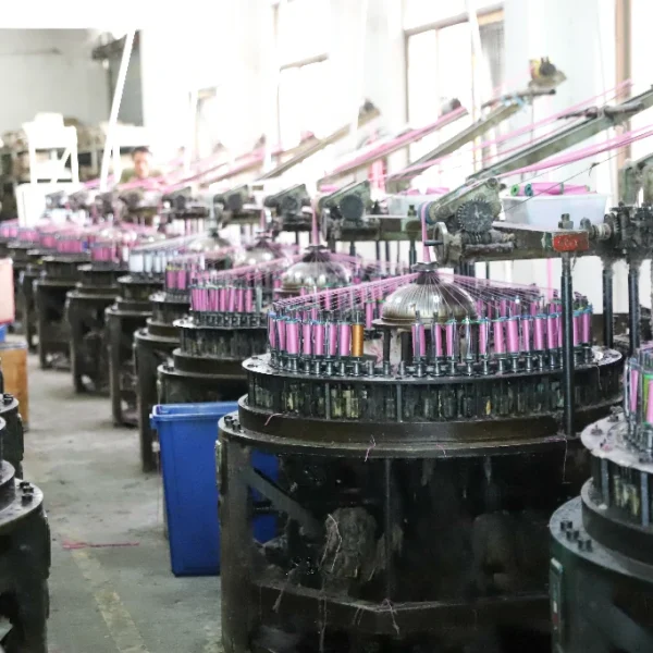 Factory floor showing a worker and weaving machinery surrounded by lace materials.