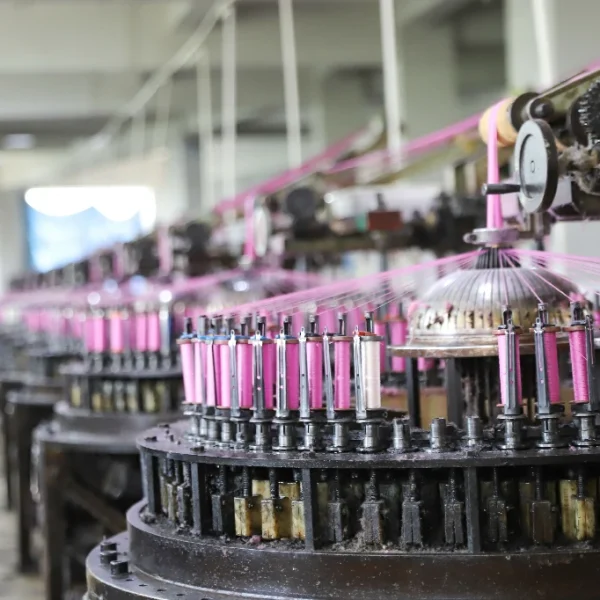 Employee managing lace weaving machine in the production workshop.