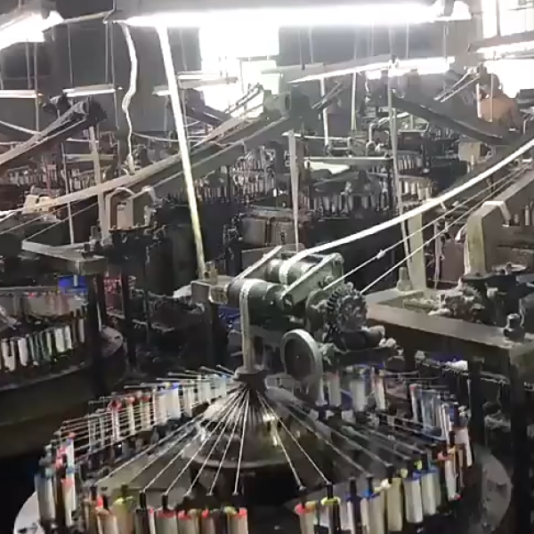 Factory setting showing technicians operating embroidery equipment to produce custom pure cotton eyelet lace with reinforced borders for garments. 提问 解释