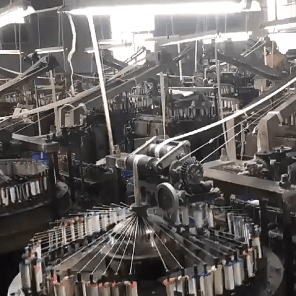 Factory setting showing technicians operating embroidery equipment to produce custom pure cotton eyelet lace with reinforced borders for garments. 提问 解释