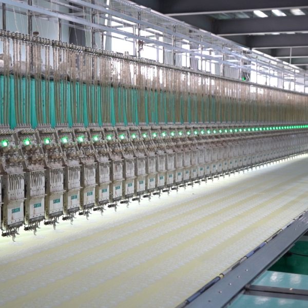 Detailed shot of embroidery machines inside a commercial lace factory producing intricate lace patterns for fashion and textiles.