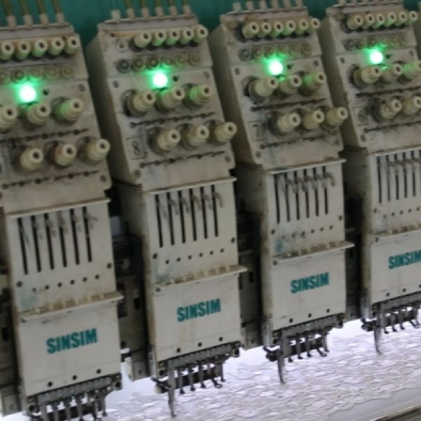 Panoramic image of a large lace manufacturing plant featuring multiple embroidery lines working simultaneously to produce fine lace products.