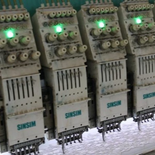 Panoramic image of a large lace manufacturing plant featuring multiple embroidery lines working simultaneously to produce fine lace products.